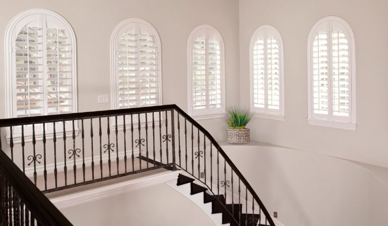 Plantation shutters on uniquely shaped windows.